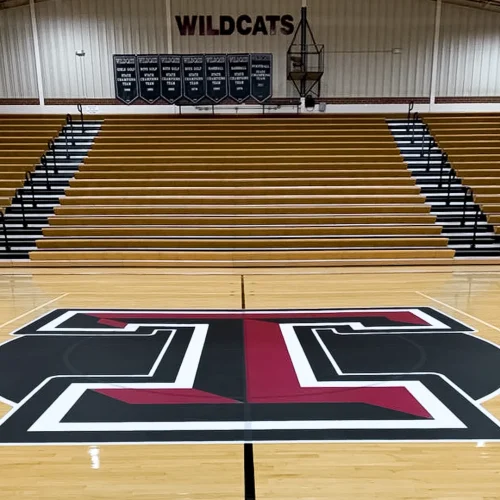 Center court floor logo installation featuring a branded ‘T’ design on hardwood basketball flooring