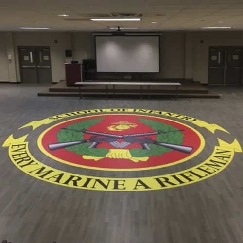 Large engineered floor graphic installed in the center of a Marine Infantry School conference hall.